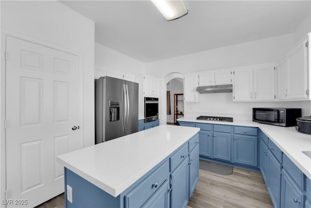 kitchen with appliances with stainless steel finishes, white cabinets, a center island, blue cabinetry, and light wood-type flooring