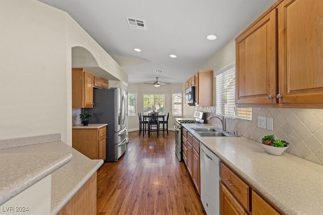 kitchen with dark wood-style floors, light countertops, decorative backsplash, appliances with stainless steel finishes, and a sink