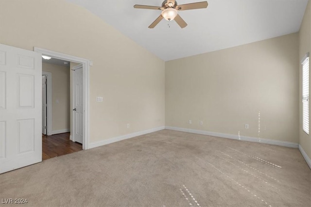 carpeted empty room with lofted ceiling, baseboards, and a ceiling fan