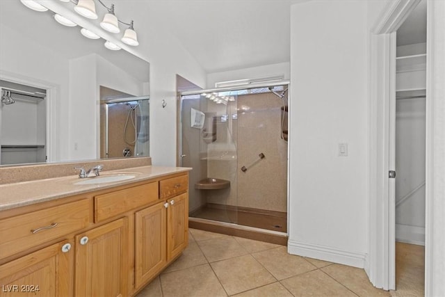 full bathroom with a stall shower, a walk in closet, vanity, and tile patterned floors