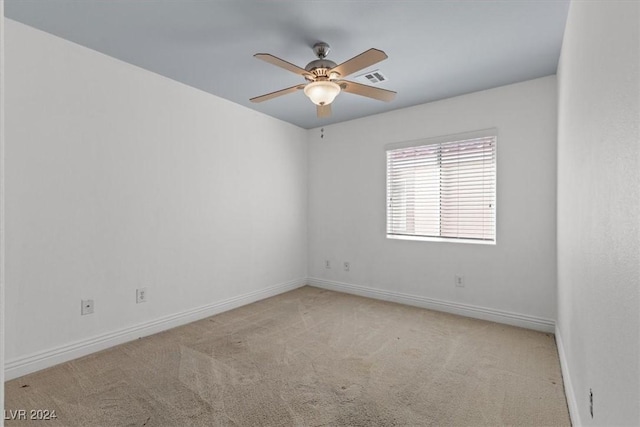 carpeted spare room with visible vents, ceiling fan, and baseboards