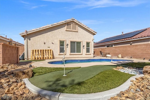 back of house with a fenced in pool, a tile roof, stucco siding, a patio area, and a fenced backyard