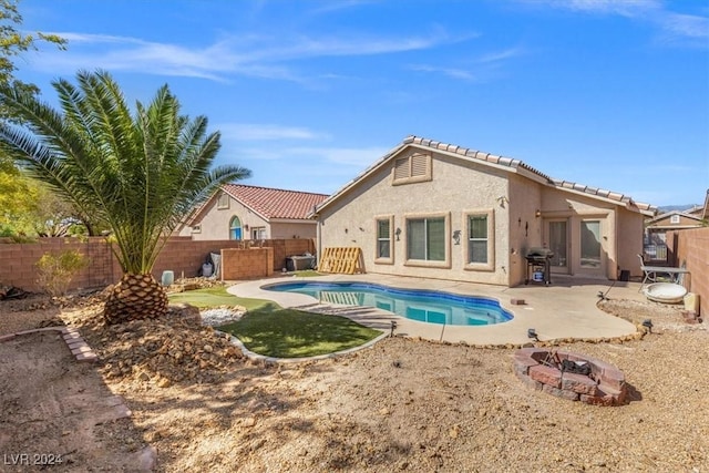 rear view of property with a fenced in pool, stucco siding, an outdoor fire pit, a patio area, and a fenced backyard