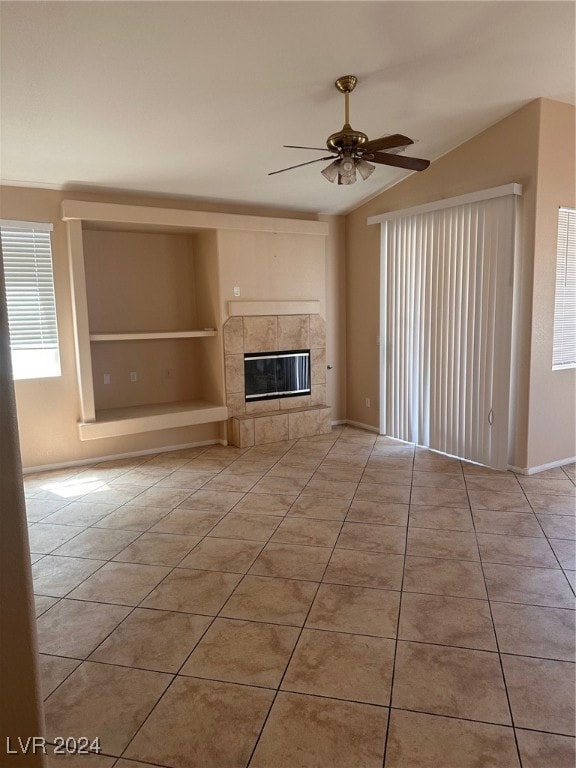 unfurnished living room featuring built in features, ceiling fan, a fireplace, and tile patterned flooring