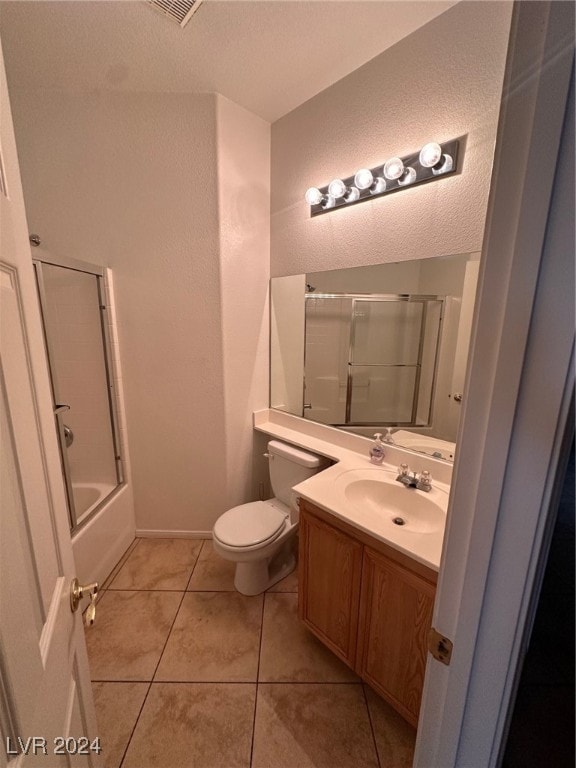 full bathroom featuring toilet, tile patterned floors, combined bath / shower with glass door, vanity, and a textured ceiling