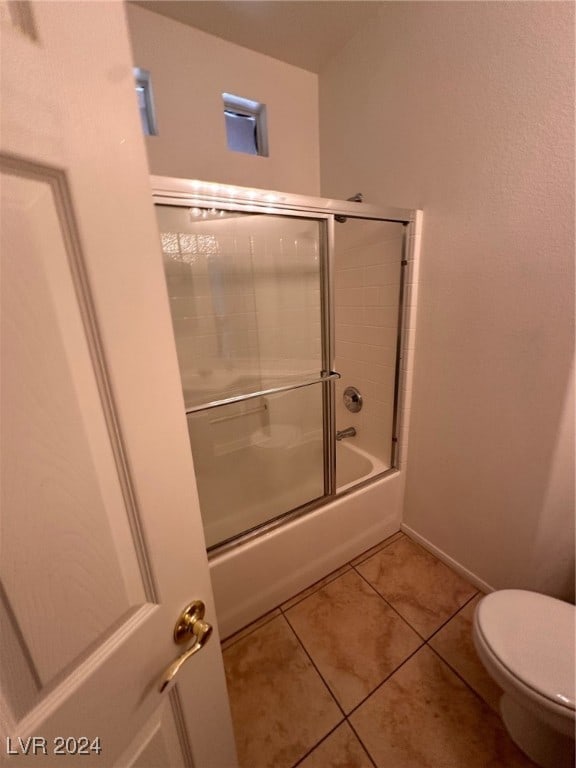 bathroom featuring combined bath / shower with glass door, toilet, and tile patterned floors