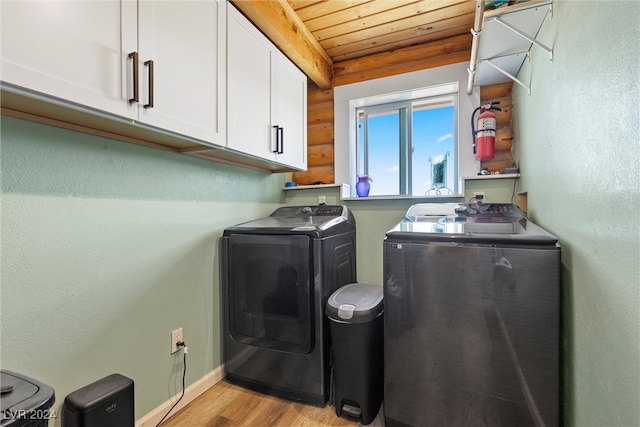 clothes washing area with light wood-type flooring, cabinets, wooden ceiling, and washing machine and clothes dryer