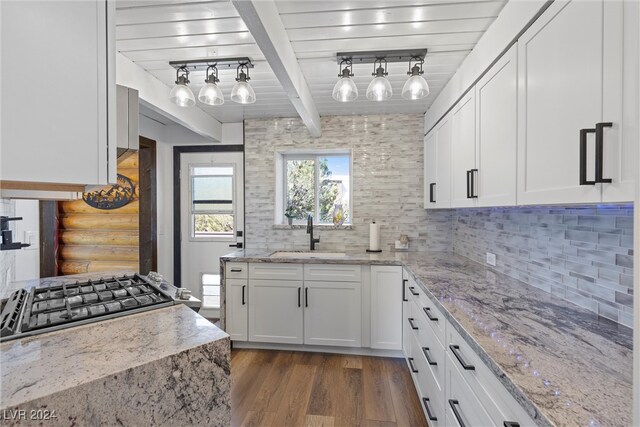 kitchen with white cabinetry, sink, light stone counters, and dark hardwood / wood-style flooring