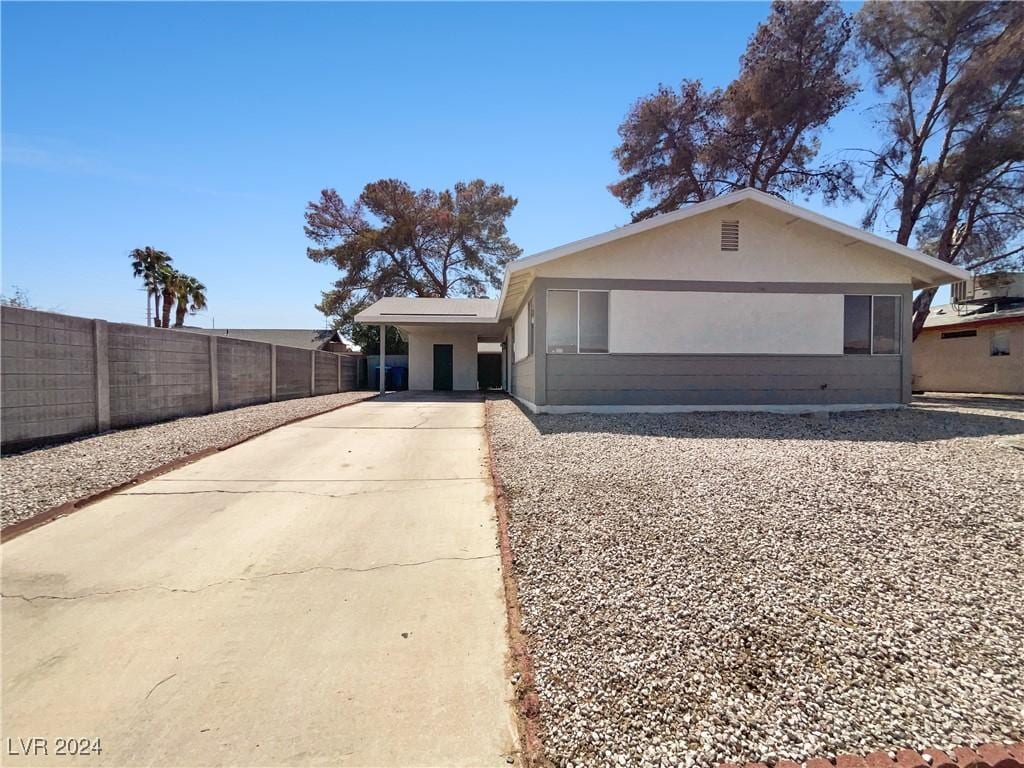 view of front facade featuring driveway, fence, and stucco siding