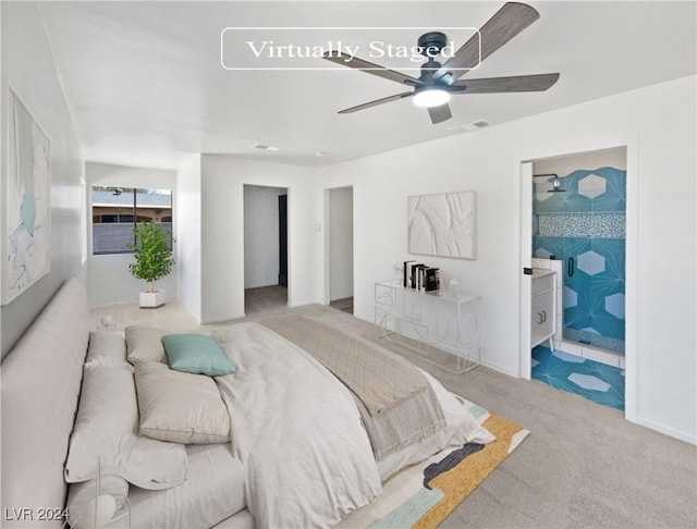 bedroom featuring light colored carpet, ensuite bath, and ceiling fan