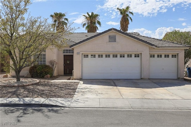 single story home with a tile roof, an attached garage, driveway, and stucco siding