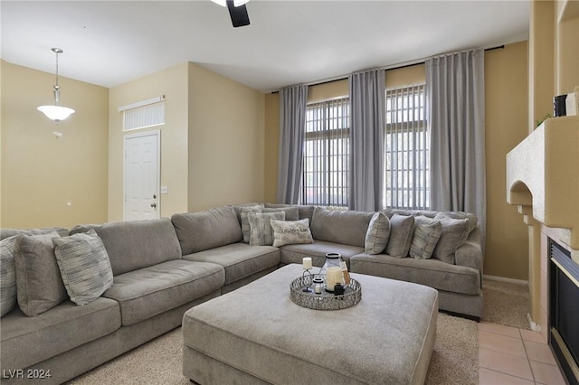 living room with light colored carpet, ceiling fan, a fireplace with flush hearth, and light tile patterned floors