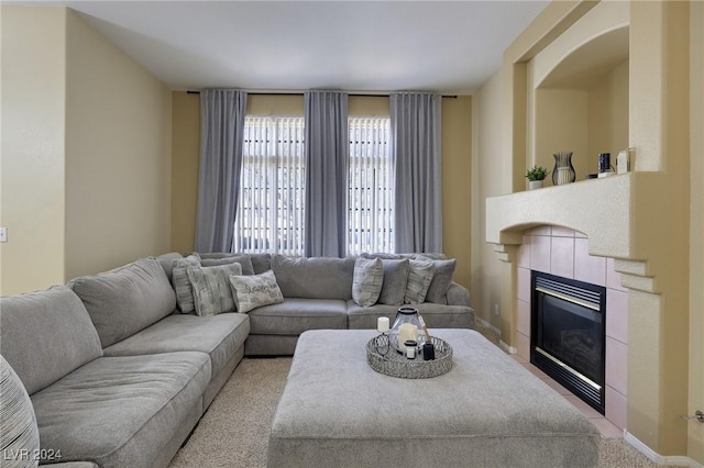 living room featuring baseboards, light carpet, and a tile fireplace