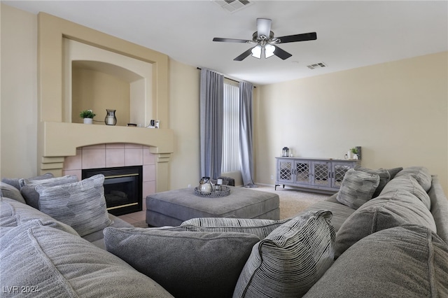 living room featuring ceiling fan, a tile fireplace, and carpet floors