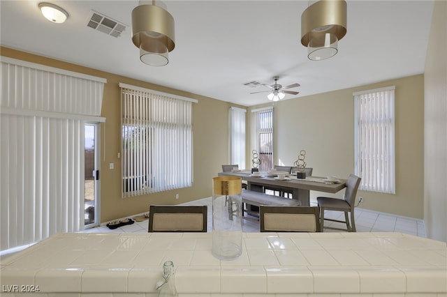 tiled dining space with a wealth of natural light and ceiling fan