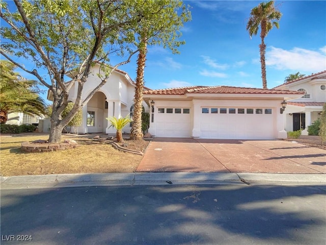 mediterranean / spanish-style house with concrete driveway, an attached garage, a tiled roof, and stucco siding