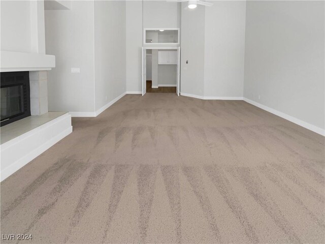 unfurnished living room with carpet floors and a tiled fireplace