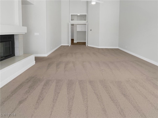 unfurnished living room featuring a fireplace, carpet flooring, and baseboards