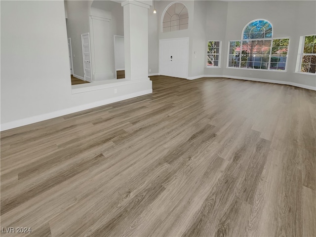 unfurnished living room with a towering ceiling and light hardwood / wood-style flooring