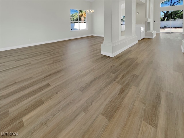 interior space with decorative columns, a healthy amount of sunlight, light hardwood / wood-style floors, and an inviting chandelier