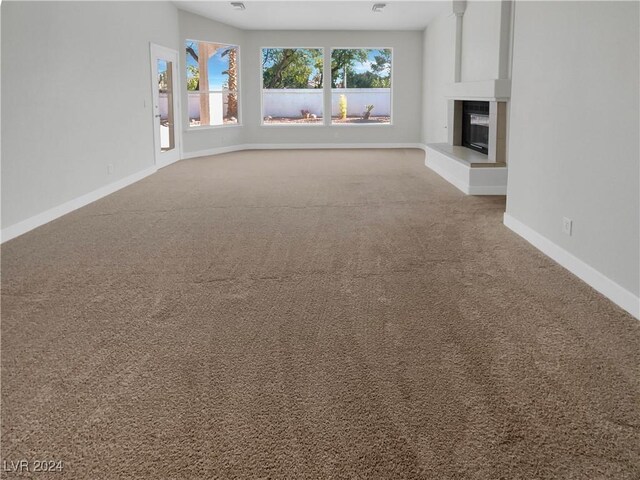 unfurnished living room featuring carpet and a tiled fireplace