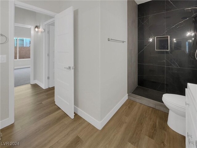 bathroom featuring tiled shower, wood-type flooring, and toilet