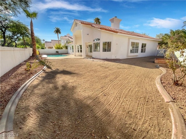 back of property with a fenced in pool and a patio area