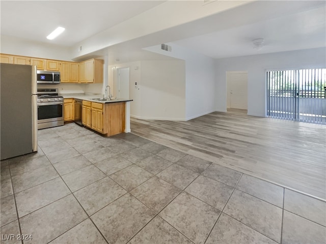 kitchen featuring light brown cabinetry, light wood-type flooring, stainless steel appliances, sink, and kitchen peninsula