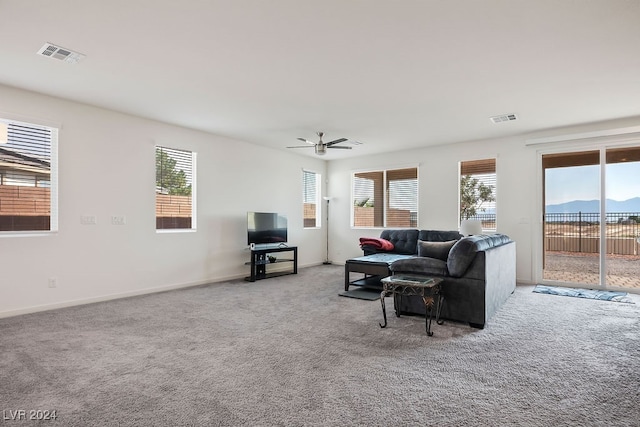 living room featuring light carpet, a healthy amount of sunlight, and ceiling fan