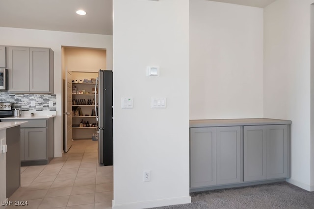 kitchen with light tile patterned floors, gray cabinets, appliances with stainless steel finishes, and decorative backsplash