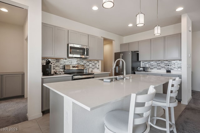 kitchen with an island with sink, a breakfast bar area, stainless steel appliances, and decorative light fixtures