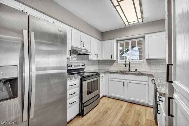 kitchen with white cabinets, light hardwood / wood-style flooring, stone counters, stainless steel appliances, and sink