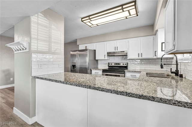 kitchen with appliances with stainless steel finishes, sink, white cabinetry, hardwood / wood-style flooring, and stone counters