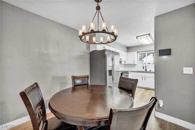 dining space with wood-type flooring, sink, and a notable chandelier