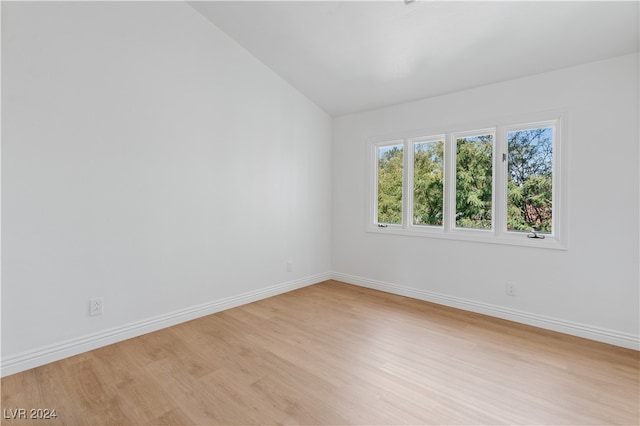 empty room with vaulted ceiling and light wood-type flooring