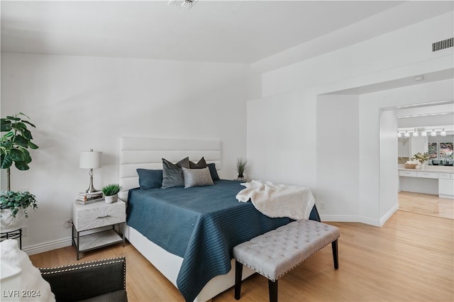 bedroom featuring hardwood / wood-style flooring and ensuite bath