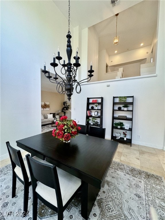 dining area featuring a towering ceiling and an inviting chandelier