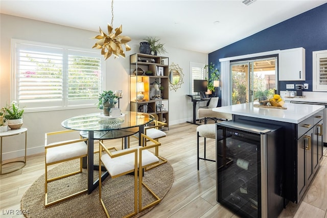 dining area with lofted ceiling, wine cooler, and light wood-type flooring