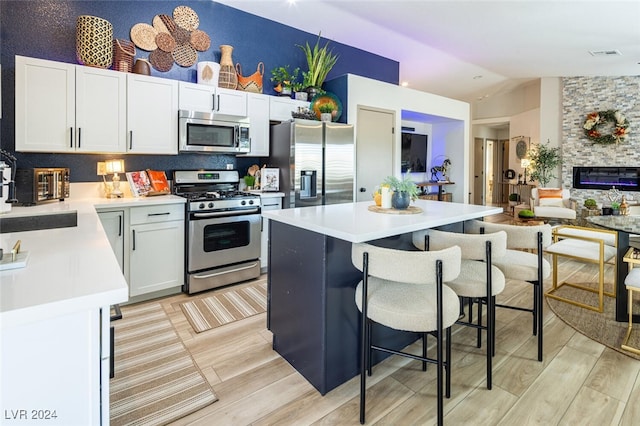 kitchen with lofted ceiling, light hardwood / wood-style flooring, a center island, and appliances with stainless steel finishes