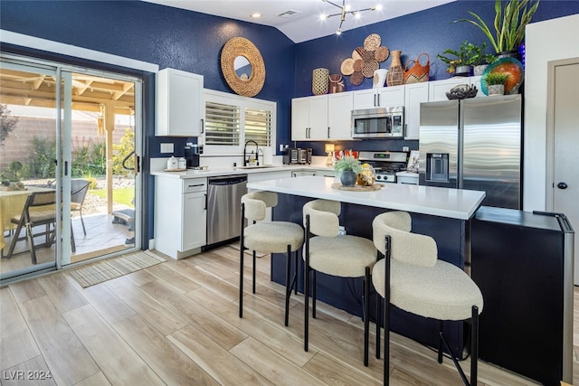 kitchen featuring plenty of natural light, a kitchen island, stainless steel appliances, and light hardwood / wood-style floors