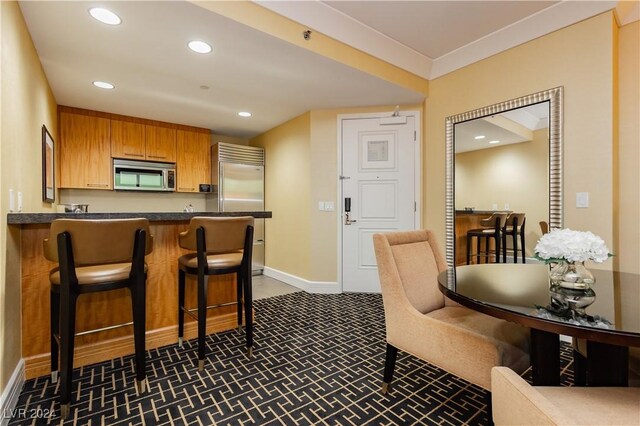 kitchen with appliances with stainless steel finishes, a kitchen breakfast bar, kitchen peninsula, and dark colored carpet