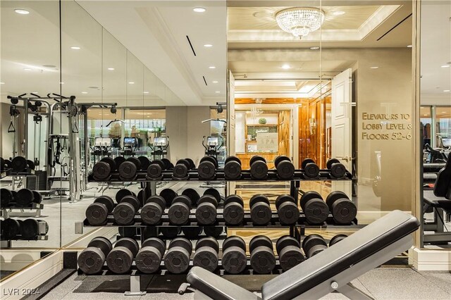 exercise room with a raised ceiling and ornamental molding