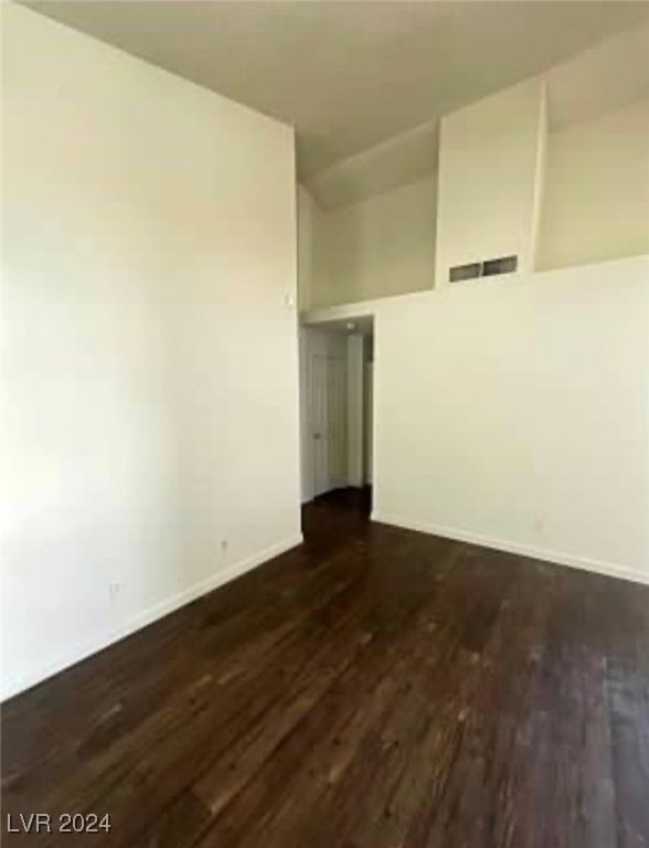 empty room featuring vaulted ceiling and dark hardwood / wood-style flooring