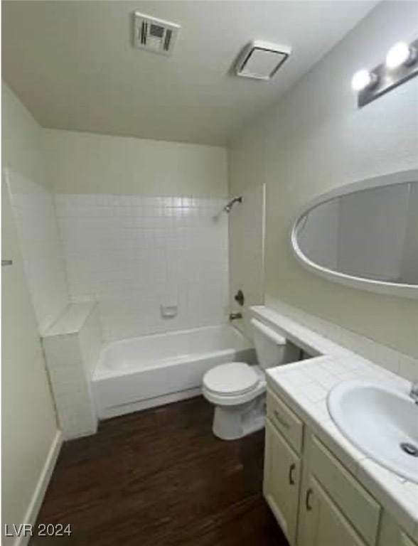 full bathroom with vanity, toilet, wood-type flooring, and tiled shower / bath