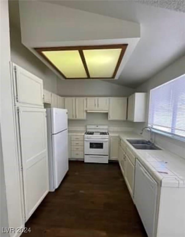 kitchen featuring vaulted ceiling, white appliances, tile countertops, sink, and white cabinets