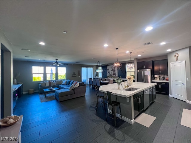 kitchen featuring stainless steel appliances, ceiling fan, sink, a breakfast bar area, and a center island with sink