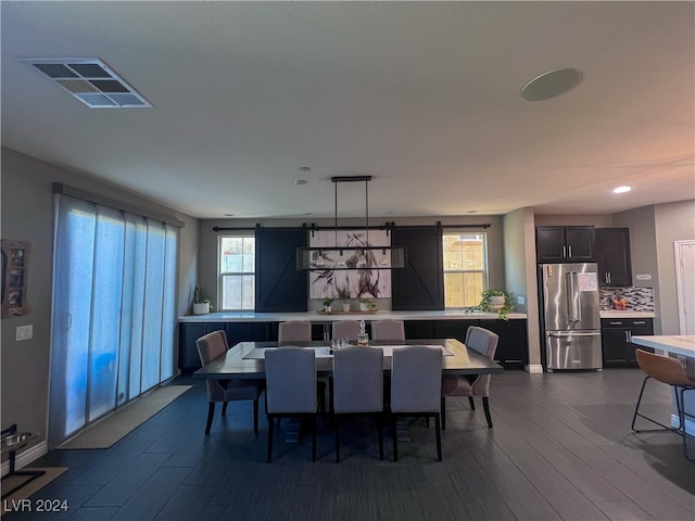 dining room featuring a barn door and dark wood-type flooring