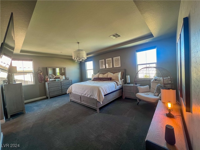 carpeted bedroom featuring a tray ceiling, a textured ceiling, and a chandelier