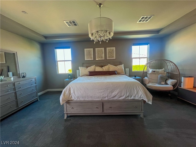 carpeted bedroom featuring a tray ceiling, an inviting chandelier, and multiple windows