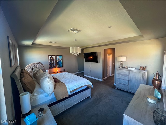 carpeted bedroom with a textured ceiling, a raised ceiling, and a chandelier